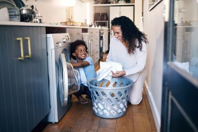 Child and adult unloading clothes dryer in kitchen